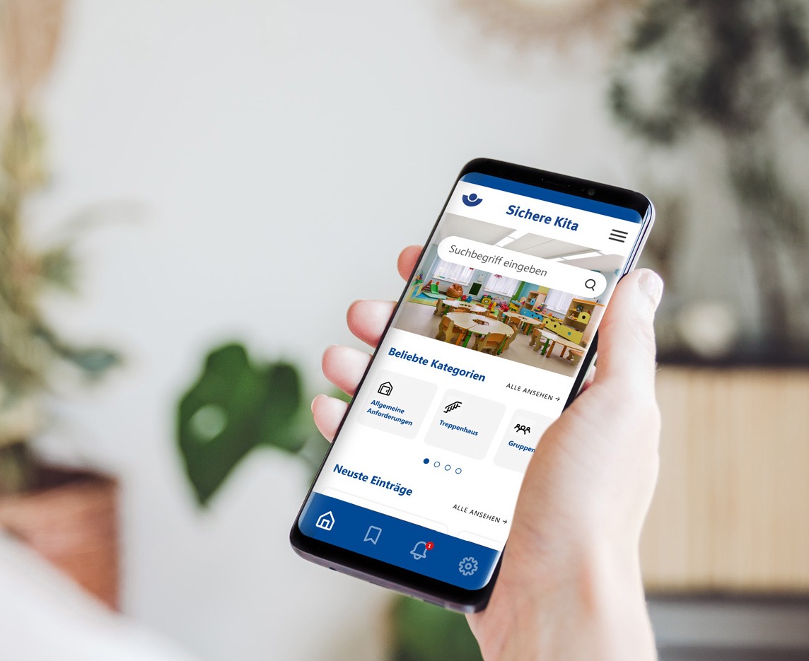 Frauenhand hält ein Smartphone und sieht die Startseite der Sichern Kita App.